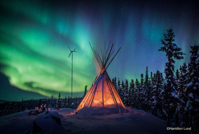 Emerald freeways dance above a tipi fire at Blachford Lake Lodge in Canada's North West Territories.  By Hamilton Lund.